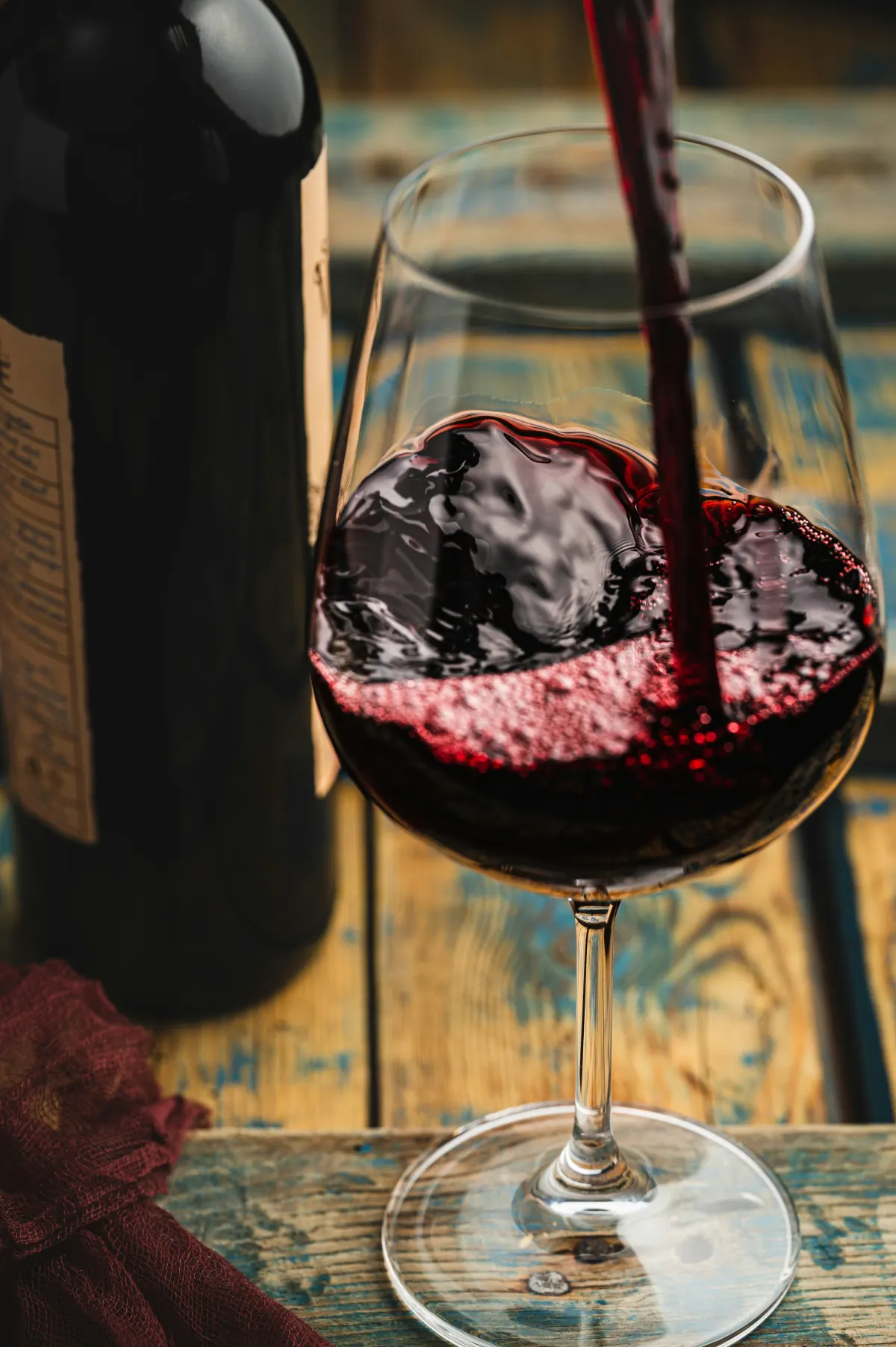Vino rosso versato in un calice, accanto alla bottiglia